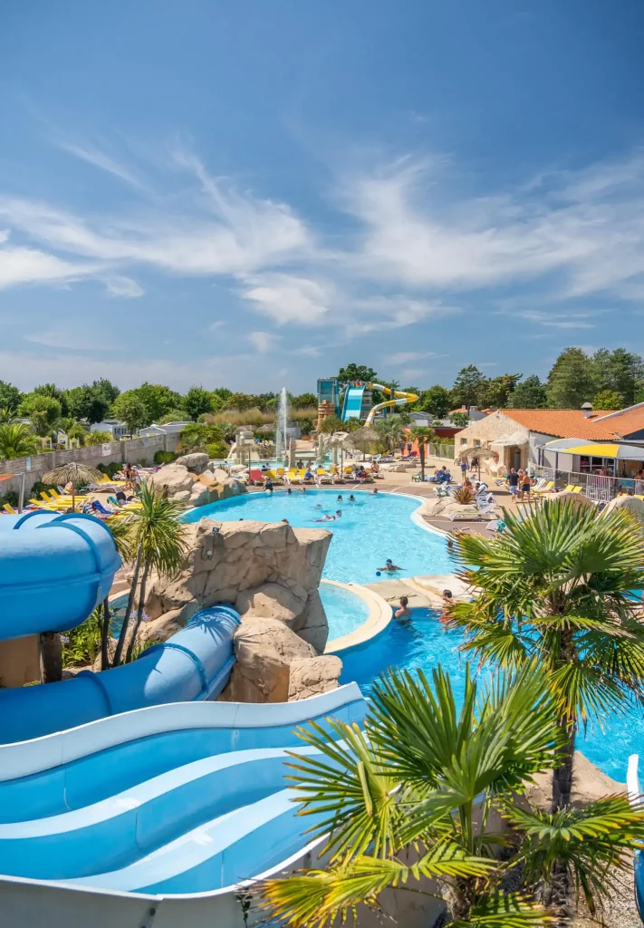 Piscine extérieure dans un camping à Saint-Jean-de-Monts, entourée de verdure et de transats.